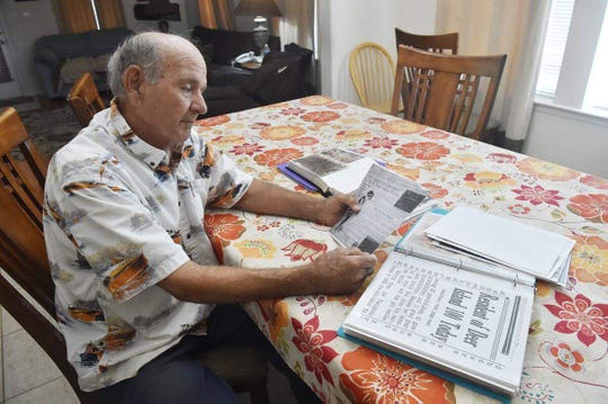 Ronald Baker looks through scrapbooks and photo albums detailing his family’s history living on Deer Island.