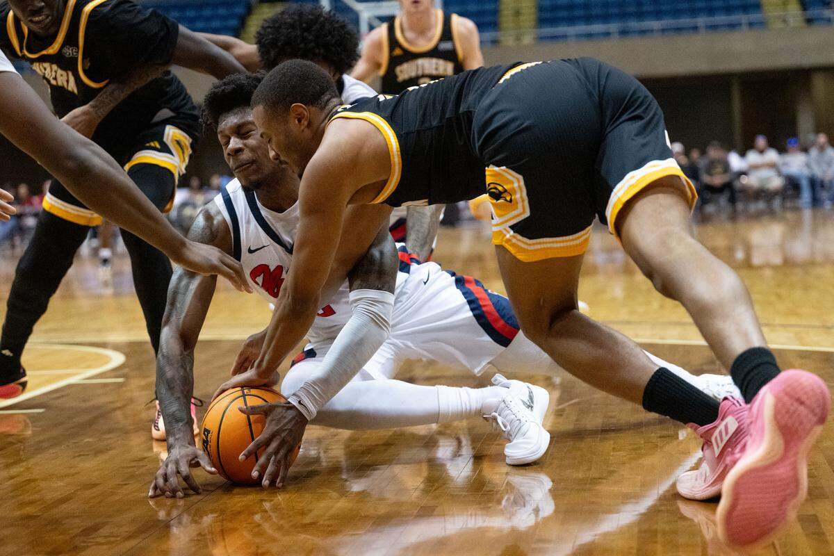 Mississippi players and Southern Mississippi players dive for a loose ball.