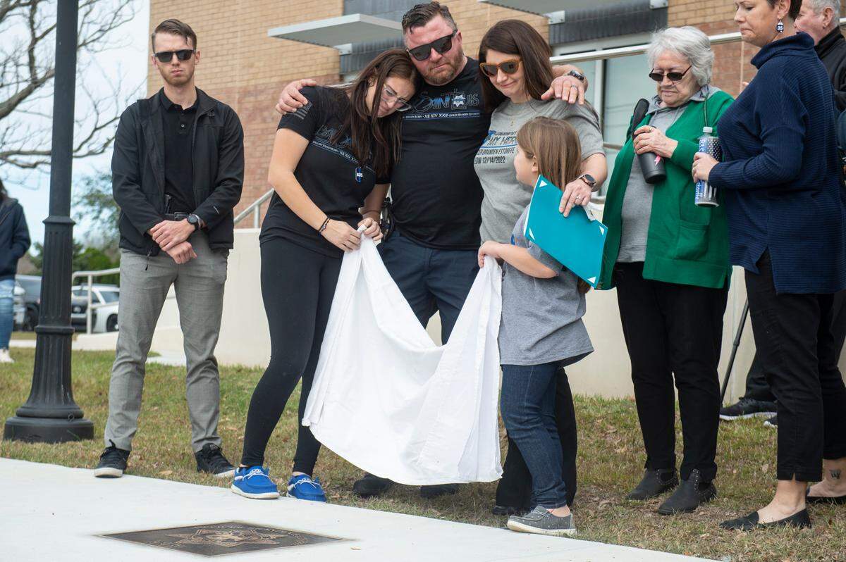 Members of Branden Estorffe’s family remove a sheet covering a metal star during a ceremony dedicating commemorative stars in honor of Sergeant Steven Robin and Officer Branden Estorffe outside the new Bay St. Louis Police Department in Bay St. Louis on Thursday, Dec. 14, 2023. Estorffe and Robin were killed on Dec. 14, 2022 by a local veterinarian when they responded to a call at a Motel 6.