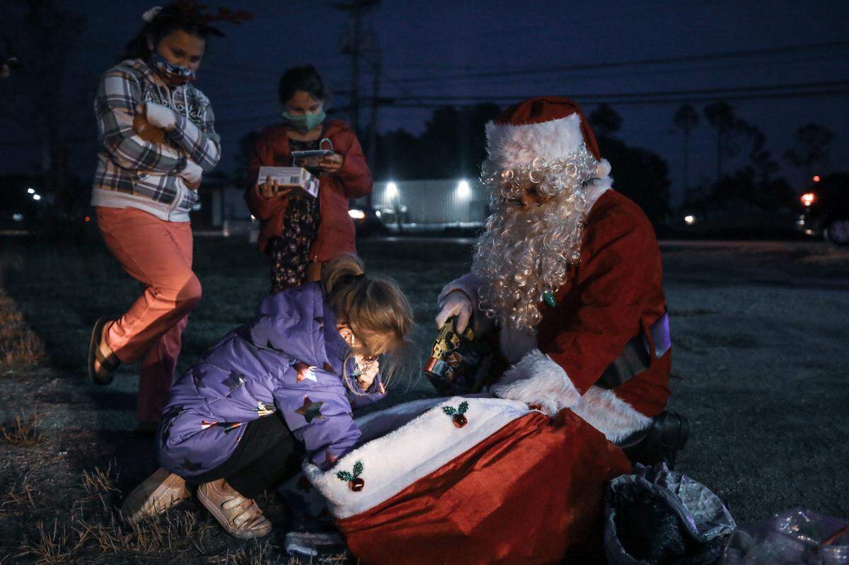 Children in Biloxi wait for a toy from Santa’s (Phil Dellenger) big red sack as the Krewe of Neptune group makes a stop outside of a neighborhood Saturday, Dec. 19, 2020.
