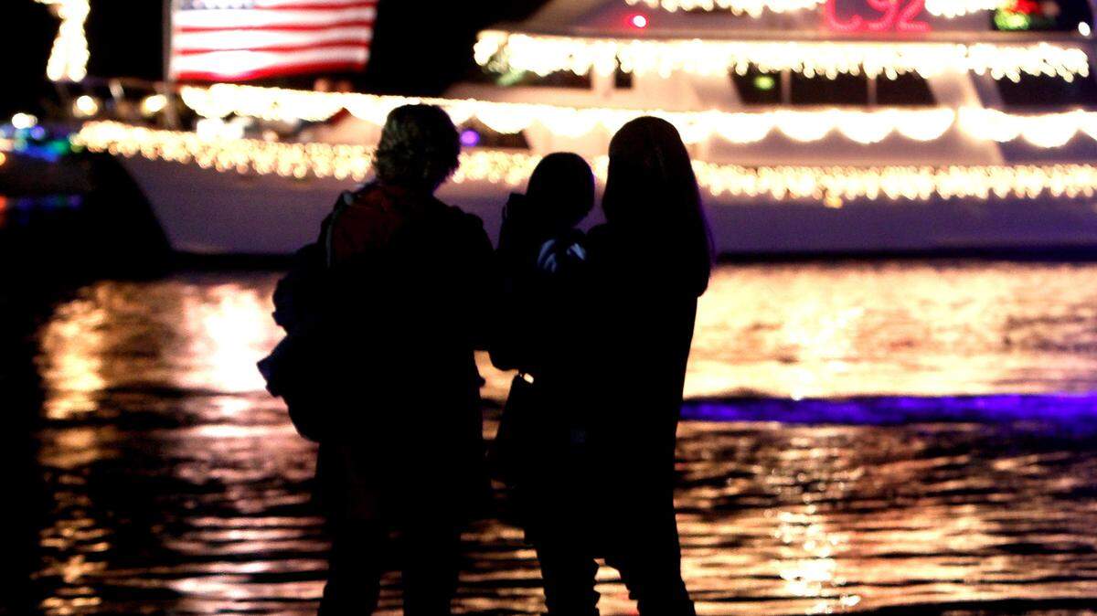 AMANDA McCOY/SUN HERALD/FILEA family watches the brightly colored boats float by during a previous year's Christmas on the Bayou. This year's annual boat parade will begin at 6 p.m. Saturday on the Gulfport Lake near The Dock Bar & Grill.