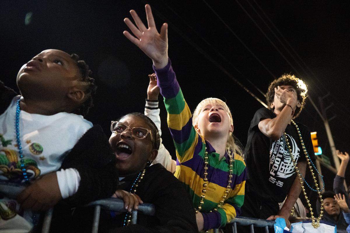 Children reach out and shout for throws from parade floats during the Krewe of Neptune parade in Biloxi on Saturday, Feb. 14, 2026.
