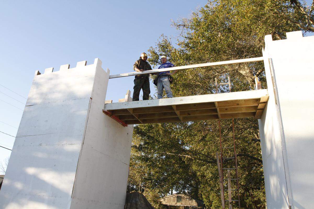 Father Jesus and Chuck Moseley stand on a second-story walkway at Father Jesus’ home in Gulfport near the Island View Casino. Father Jesus is building castle walls on the outside of his home. It meets code, the city says.