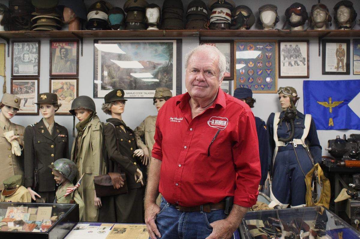 Doug “Paul” Mansfield stands beside mannequins dressed in women’s military uniforms from various war eras. His G.I. Museum, home to over 16,000 pieces of memorabilia, honors the men and women who served throughout U.S. history.