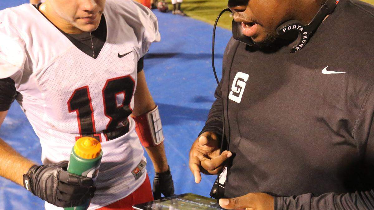 JOHN FITZHUGH/SUN HERALD 
 St. Stanislaus defensive coordinator Rashad Dunn shows linebacker Mitchell Walk a play on a tablet during the second quarter of the Shrimp Bowl against Gulfport at Milner Stadium in Gulfport on Aug. 21.