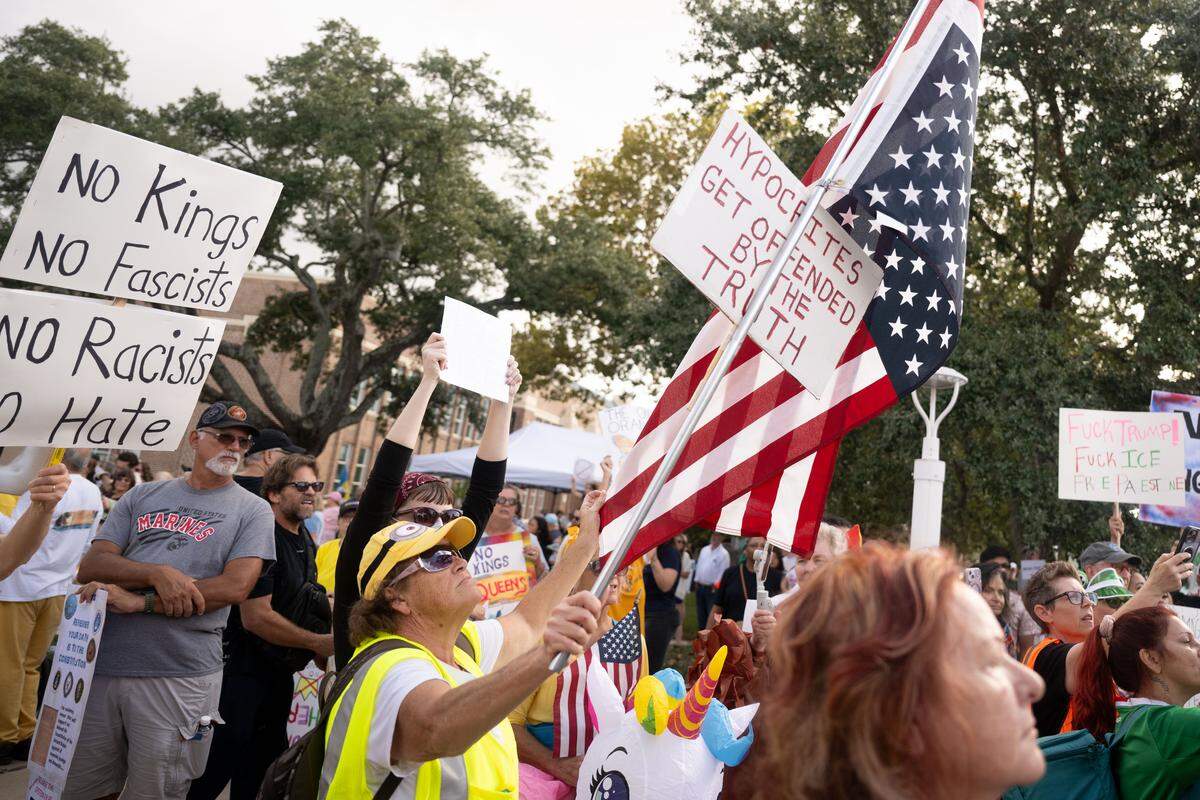 Protesters hold up signs and American flags during the No Kings protest in Gulfport.