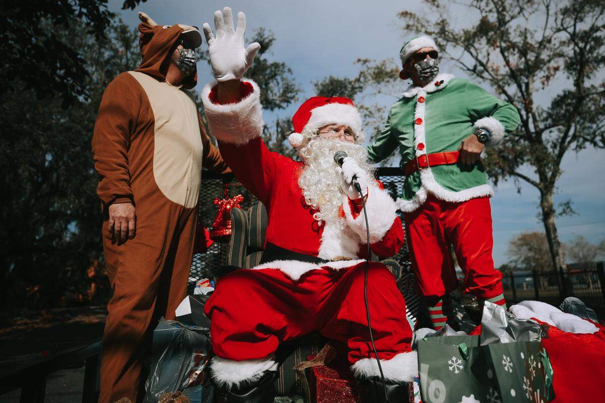 Krewe of Neptune members Robert Guentz (reindeer), Phil Dellenger (Santa) and Marques Thomas (elf) ride on a decked-out trailer to a child’s home for an early Christmas surprise Saturday, Dec. 19, 2020. The group sang carols and wished neighbors a Merry Christmas from a loudspeaker in the bed of the truck.