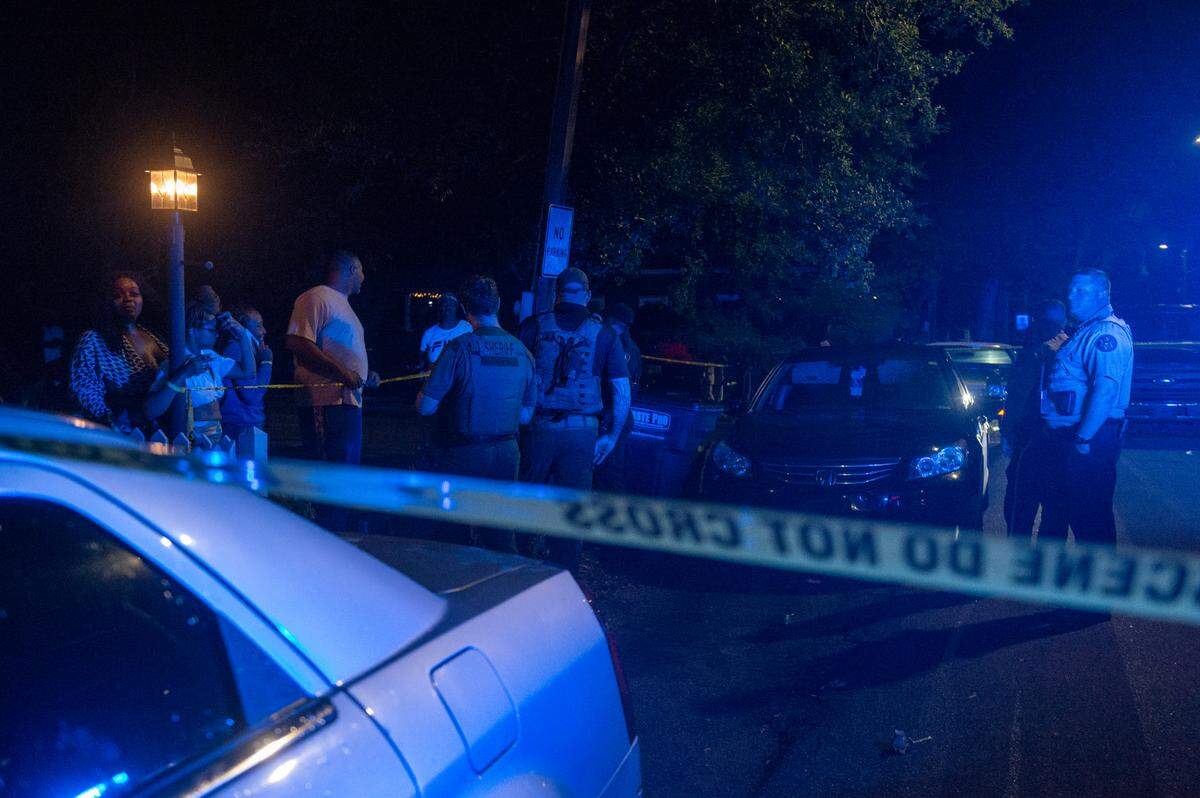 Law enforcement officers stand behind crime scene tape as onlookers watch an investigation into a shooting at The Scratch Kitchen restaurant in Ocean Springs on Friday, May 5, 2023.