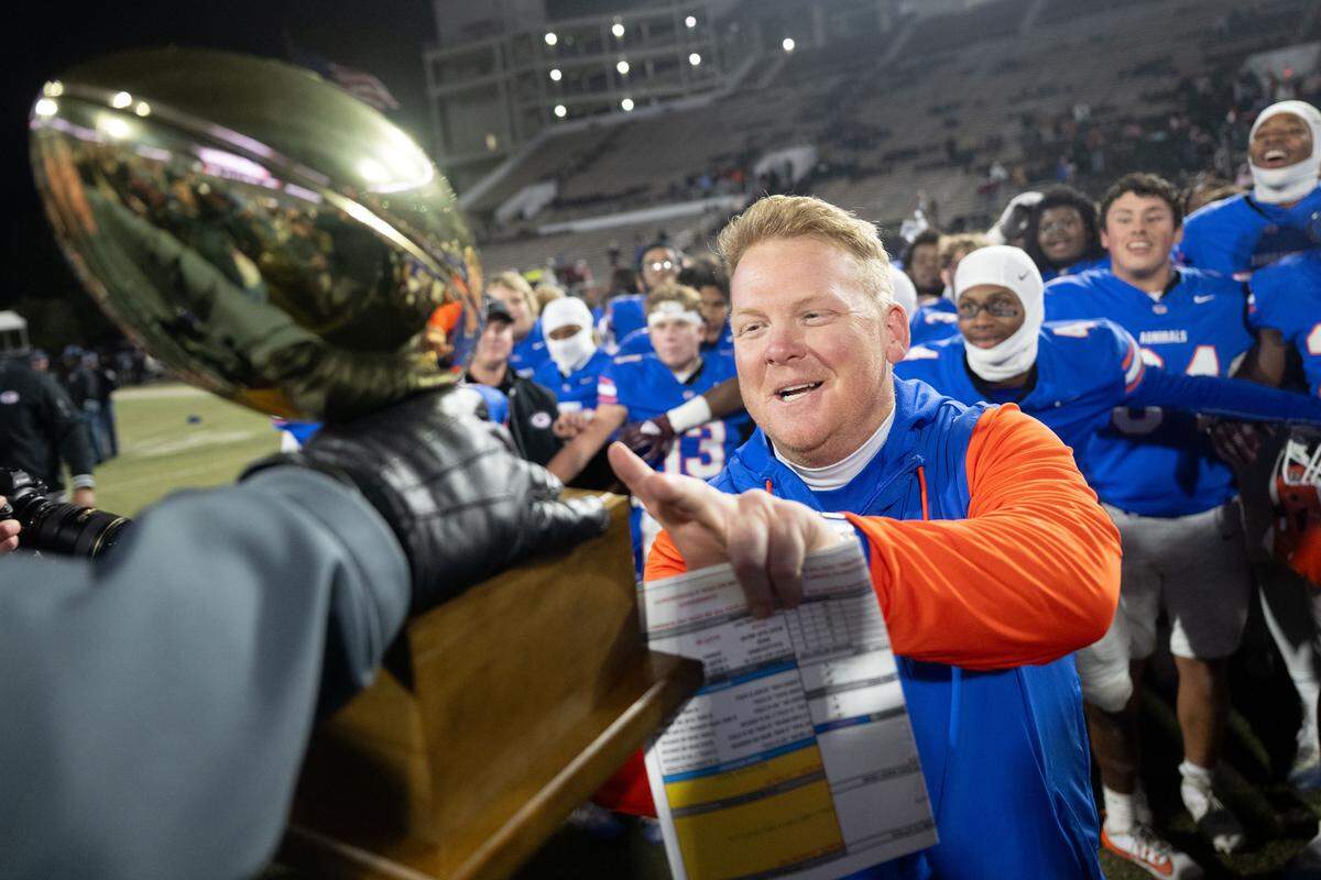 Gulfport head coach Blake Pennock accepts the Division 7A state champion trophy after the Admirals’ 21-20 win over Tupelo in Starkville.