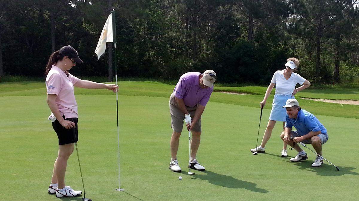 LINDSAY KNOWLES/SPECIAL TO THE SUN HERALD/FILE 
 Kate Dennis Spear holds the flag as Dave Dennis makes a putt and teammates Denise and Randy Doyle look at the ninth annual Jolly McCarty Memorial Golf Tournament at Shell Landing in Gautier in 2013.