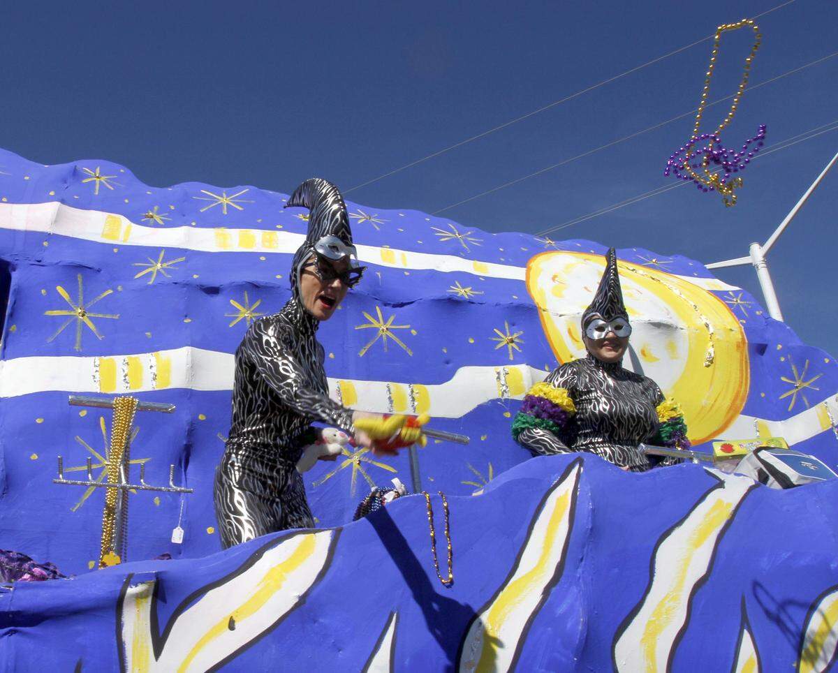 As floats move down U. S. 90, revelers toss beads to people lining the parade route at the 2013 Nereids Mardi Gras parade. Costumes often are worn by people on the floats and occasionally by those in the crowds.