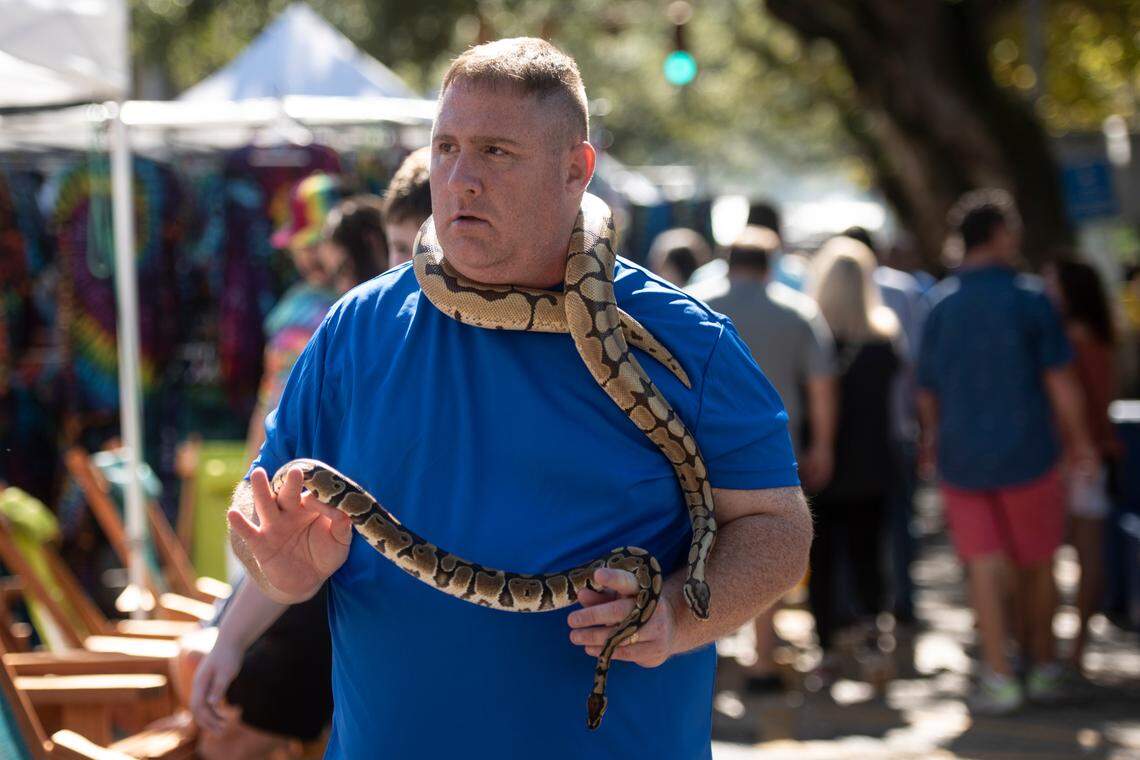 Patrick Rosado walks down Washington Avenue with his snakes Triton and Zeus during the Peter Anderson Festival in Ocean Springs on Sunday, Nov. 6, 2022.