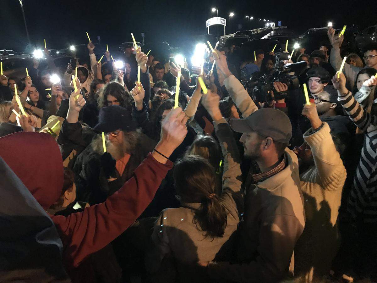 Friends and family of shooting victim Madison Harris, 16, of Biloxi hold up glow sticks during a candlelight vigil beside the beach at the Biloxi Lighthouse. Five teens were charged with capital murder in the case after Madison died Monday during surgery.