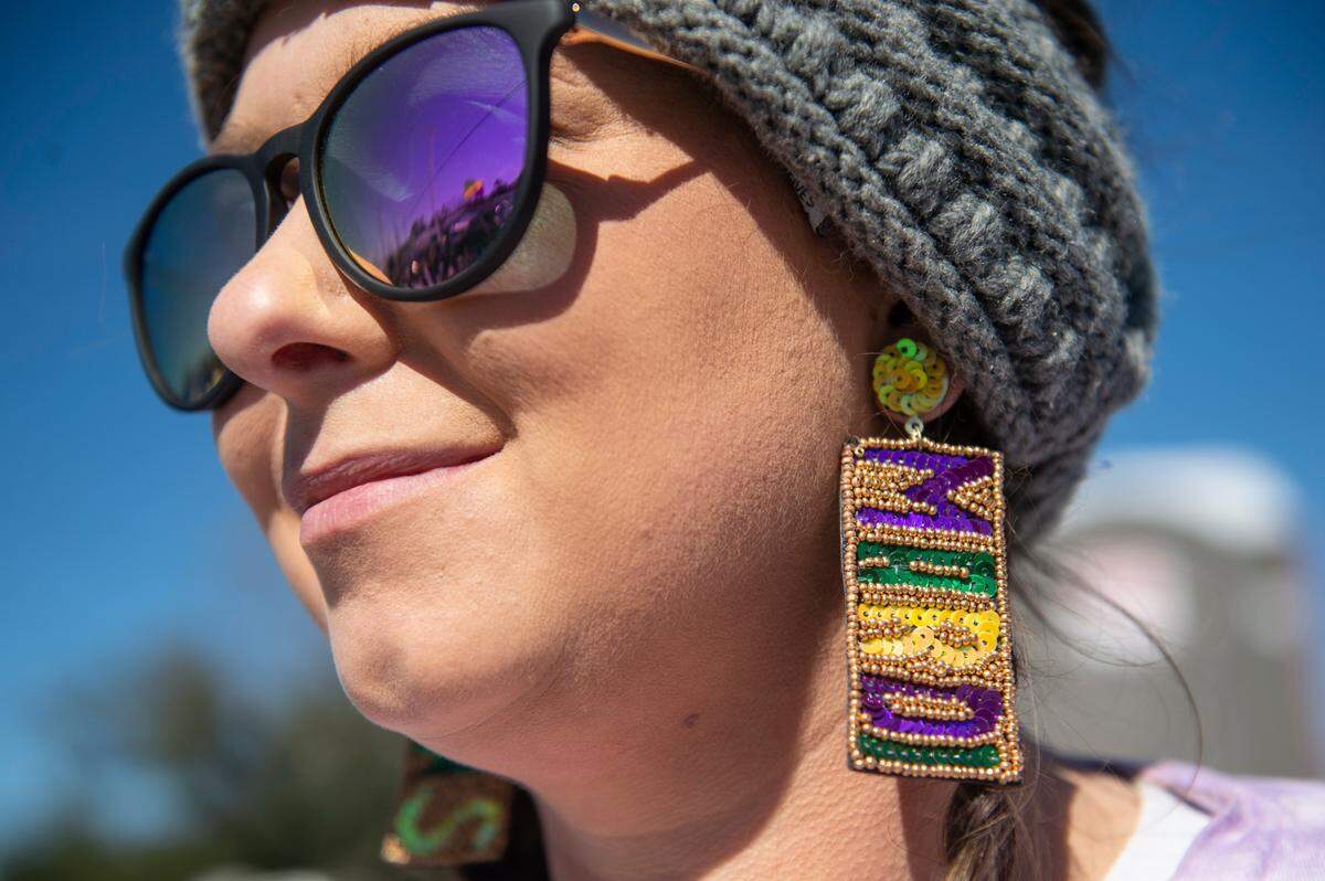 April Kingston, of Bay St. Louis, wears Mardi Gras earrings while watching the Krewe of Nereids Mardi Gras parade on Highway 90 in Bay St. Louis on Sunday, Feb. 12, 2023.
