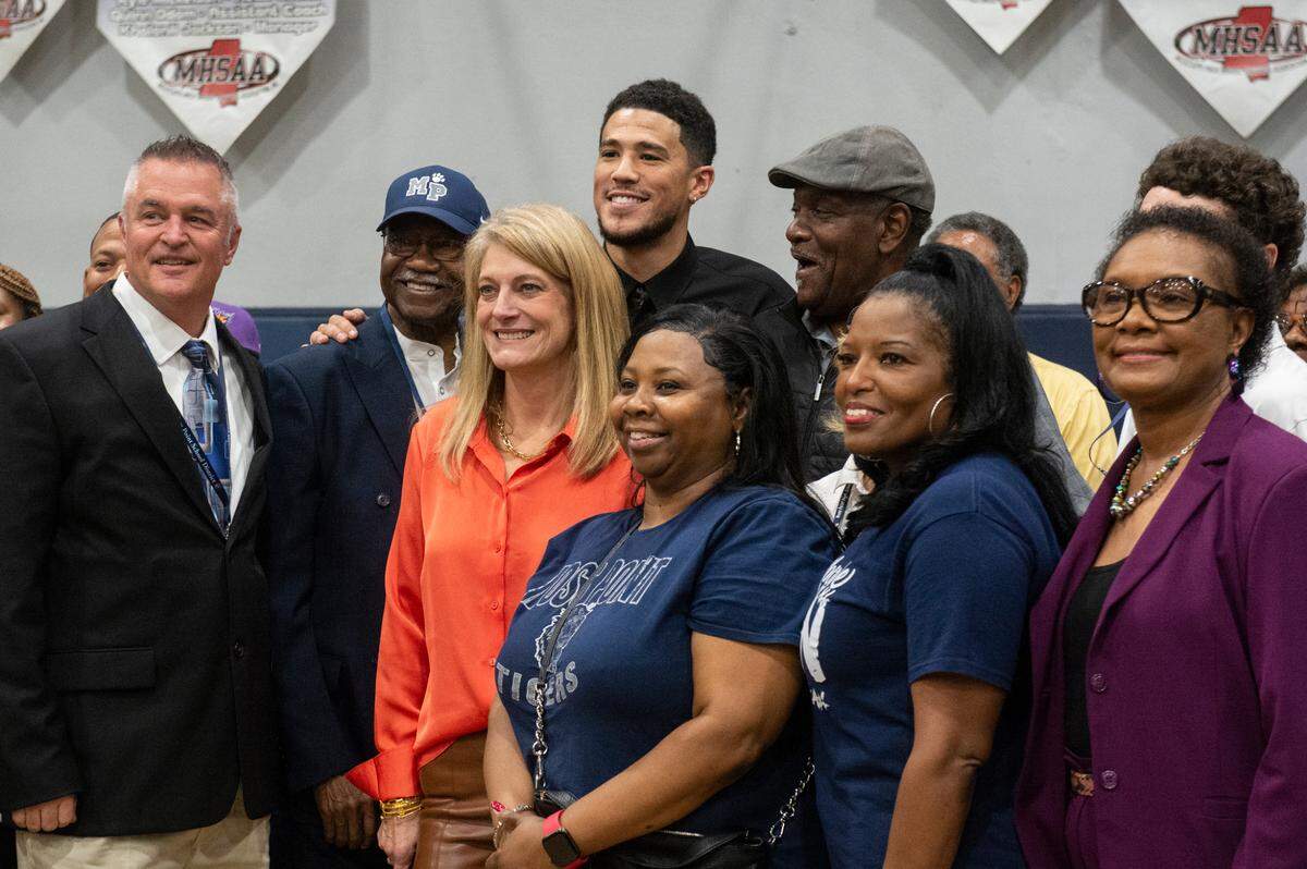 NBA star Devin Booker poses for a photo with Moss Point administrators and teachers during a ceremony for the retirement of Booker’s high school jersey at Moss Point High School in Moss Point on Saturday, Dec. 10, 2022.