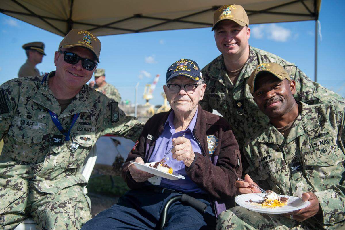 Alfred Lewis, a WWII veteran who turns 98 on March 25, poses with current US Navy members at Singing River Island in Pascagoula on Saturday, March 22, 2025.