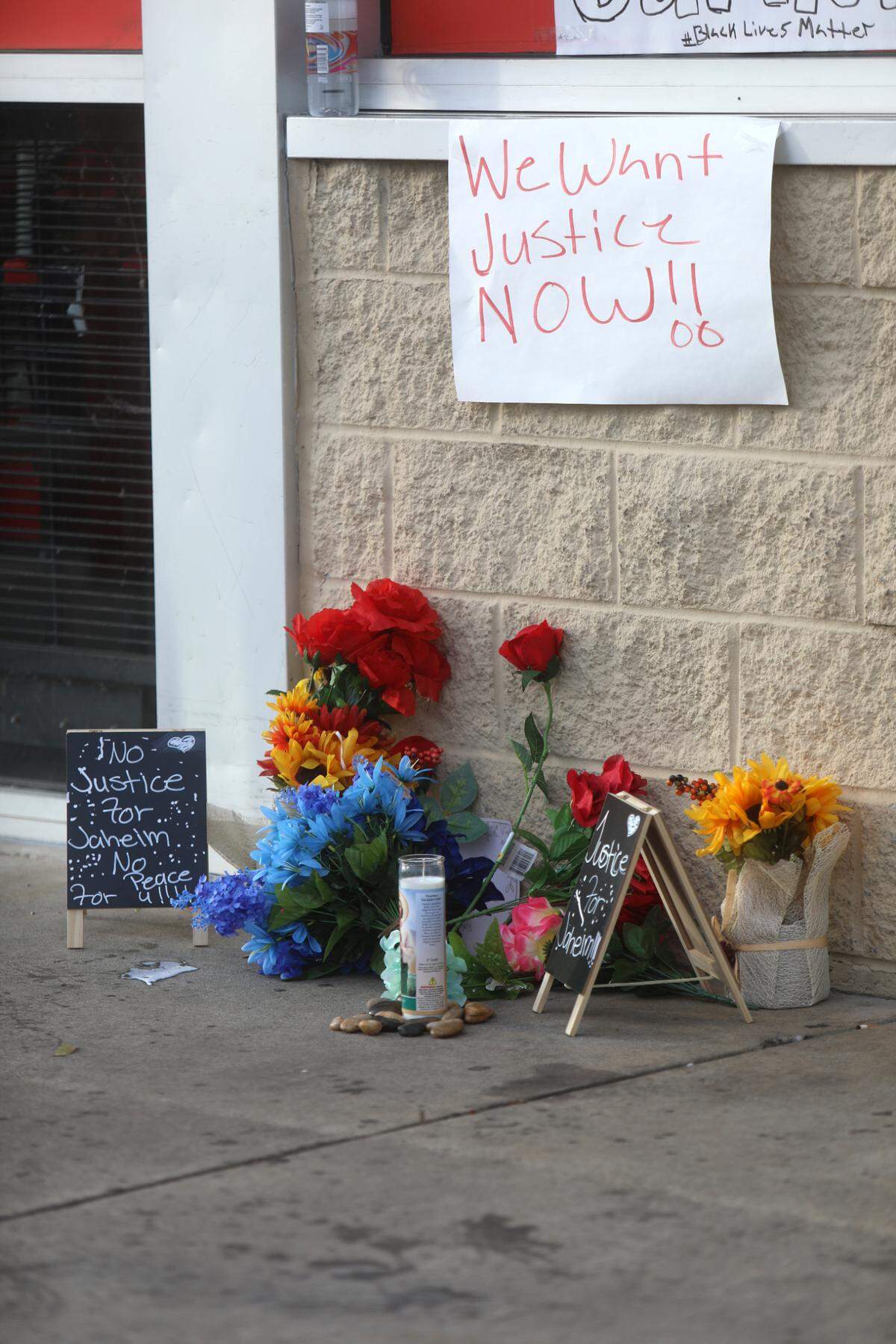 A memorial of flowers and signs that demand justice for Jaheim McMillan sits near the entrance of Family Dollar on Pass Road in Gulfport. The 15-year-old died after being shot in the head by a police officer.