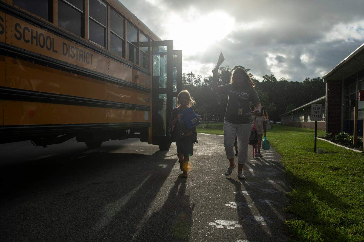 Teachers aids and staff escort kids into the building during the first day of school at Magnolia Park Elementary in Ocean Springs on Friday, Aug. 5, 2022.