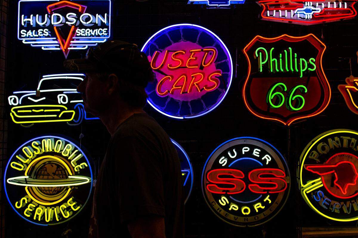 A man walks past neon signs for sale at the Cruisin’ The Coast Swap Meet at the Mississippi Coast Coliseum on Thursday, Oct. 7, 2021.