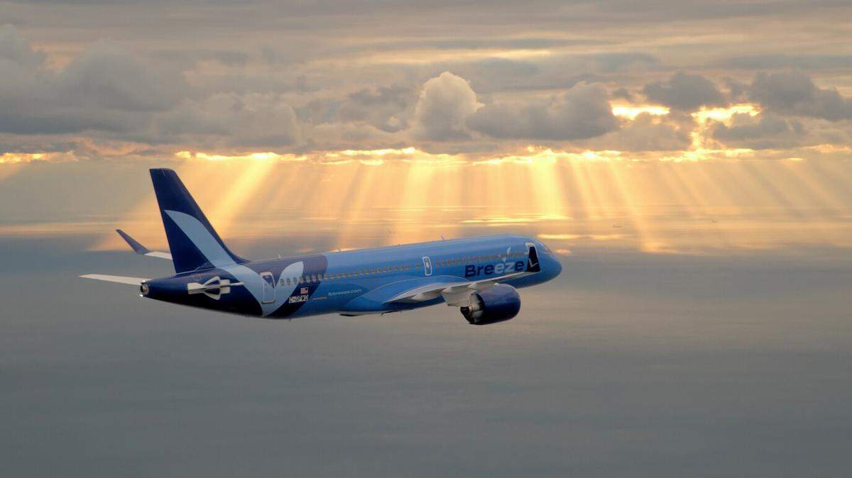 A Breeze Airways plane flies into the sunset. The carrier will begin flying non-stop to Akron Ohio, Scranton Pennsylvania and Westchester County, New York.