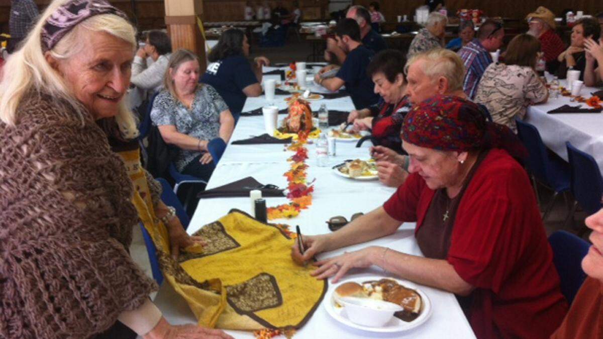 COURTESY NANCY KELLY BOSARGE 
 Guests at the Kelly Family Thanksgiving in Bay St. Louis sign Sally Kelly's apron. The family matriarch continues to solicit donations for the free communitywide meal and to hand out flyers inviting everyone to attend.