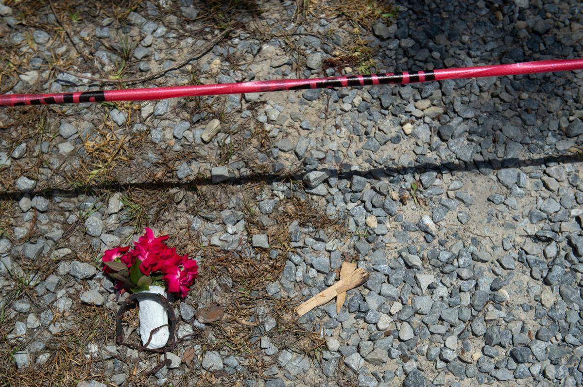 Flowers and a bracelet were left outside in front of crime scene tape next to two burned houses on Highway 603 in Kiln on Tuesday, May 31, 2022. A fire consumed the two houses on Saturday night, killing two.