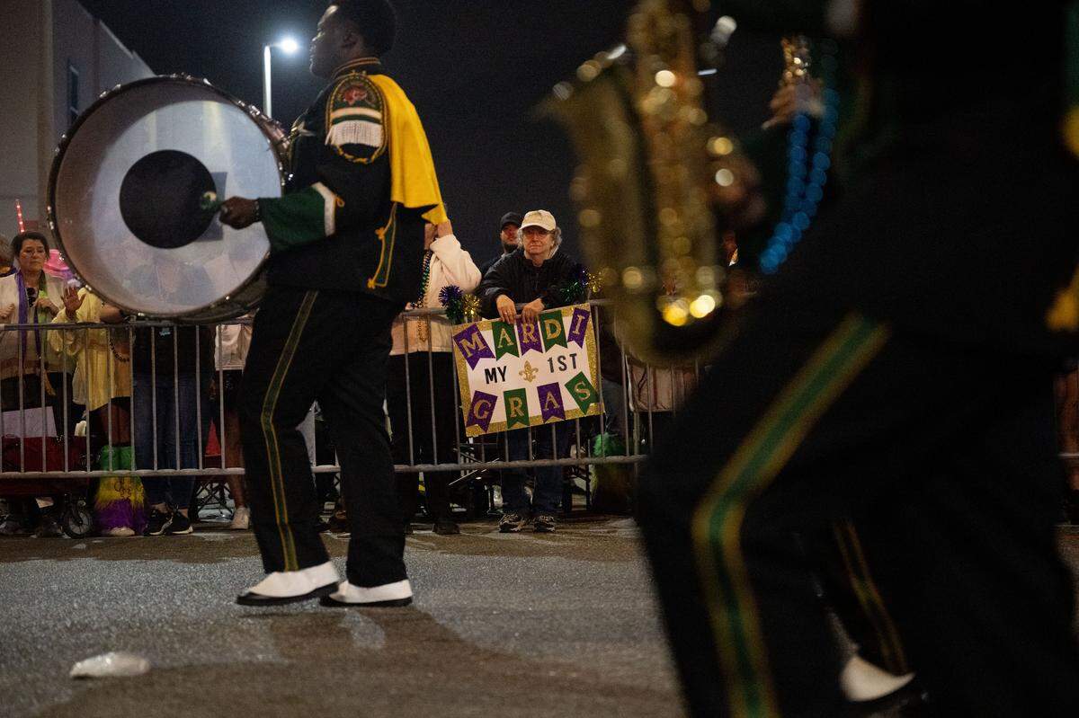 A man holds up a sign as he celebrates his first Mardi Gras during the Krewe of Neptune parade in Biloxi on Saturday, Feb. 14, 2026.