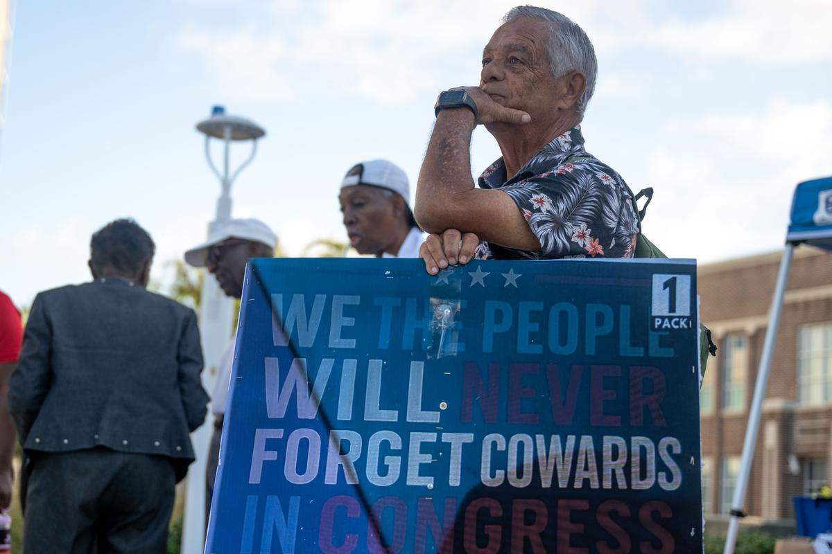 A protester holds up a sign during a No Kings protest in Gulfport.
