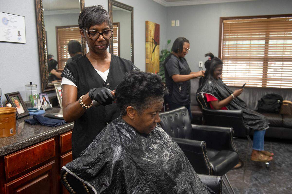 Tyrone Burton’s, daughter, left, works on a customers hair at Tyrone’s Barber and Beauty Salon in Biloxi on Wednesday, May 21, 2025. Burton has been a barber in Biloxi for 64 years and has made it a family business.
