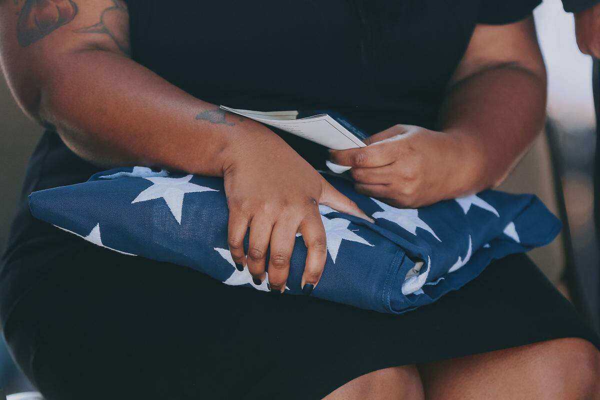 A family member of Lt. Michael Boutte holds the folded American flag at his funeral on Tuesday, Feb. 9, 2021.
