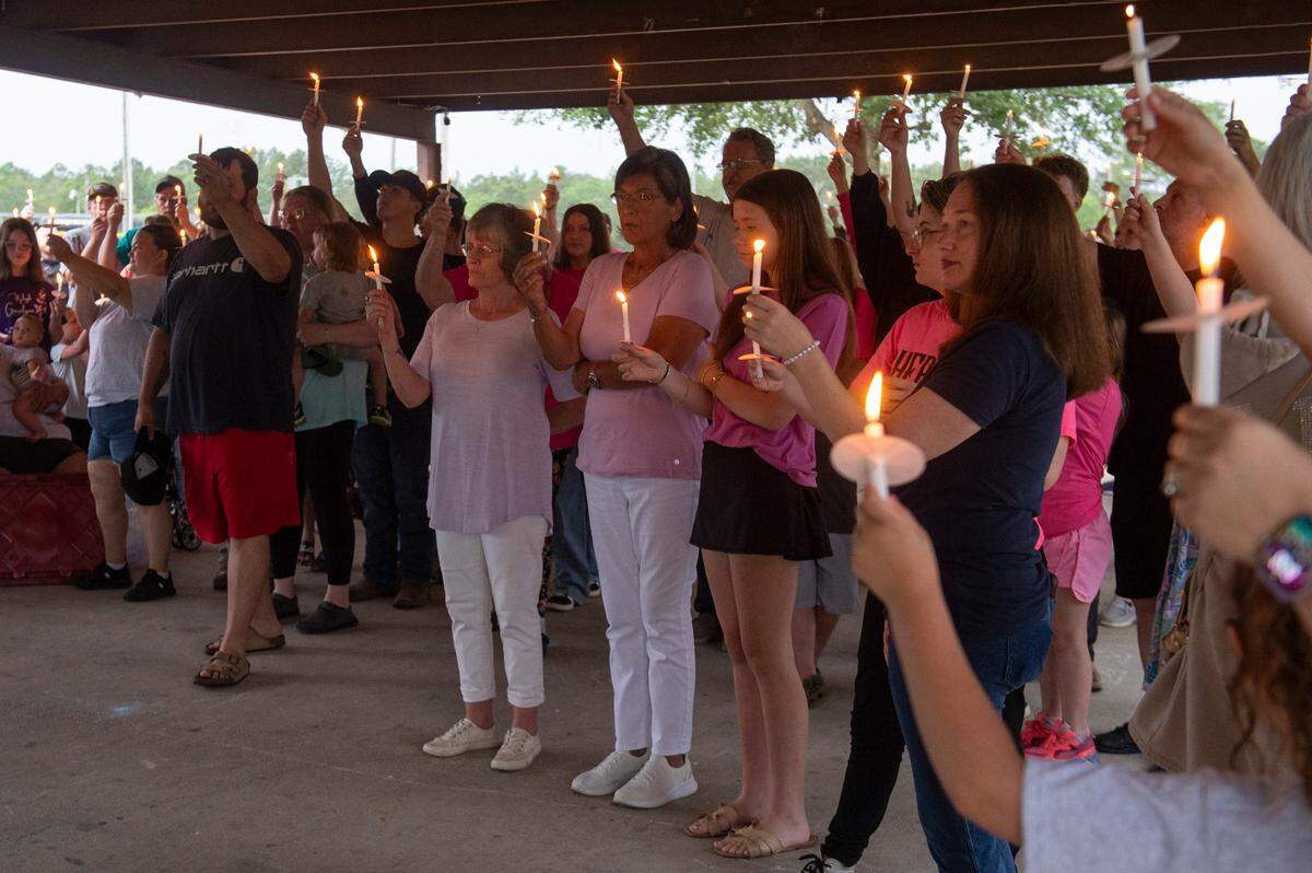 Community members raise candles in honor of Gracelynn Vick at a candlelight vigil remembering her at Saucier Park on Tuesday, April 22, 2025.