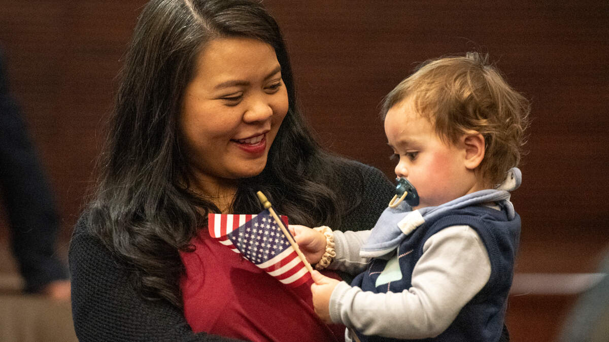 Maria Adams, an immigrant from the Philippines, holds her son Clyde Adams as he waves an American flag after Adams because a naturalized American citizen in a ceremony at Dan M. Russell Courthouse in Gulfport on Thursday, Oct. 19, 2023.