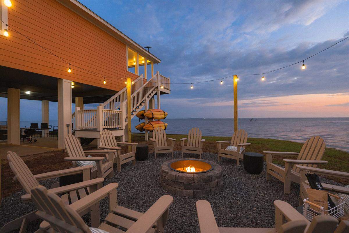 String lights and a circle of 10 adirondack chairs set the mood for a night of s’mores around a blazing fire pit at the Ocean Springs House.