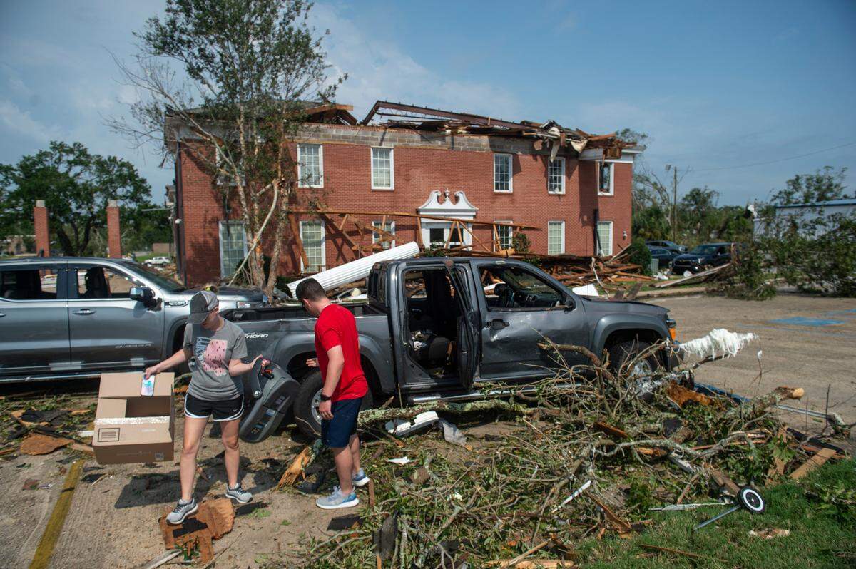 Workers salvage personal belongings from their damaged vehicles outside of Merchants and Marine Bank in Moss Point on Tuesday, June 20, 2023, after a tornado damaged the building on Monday, trapping workers inside.