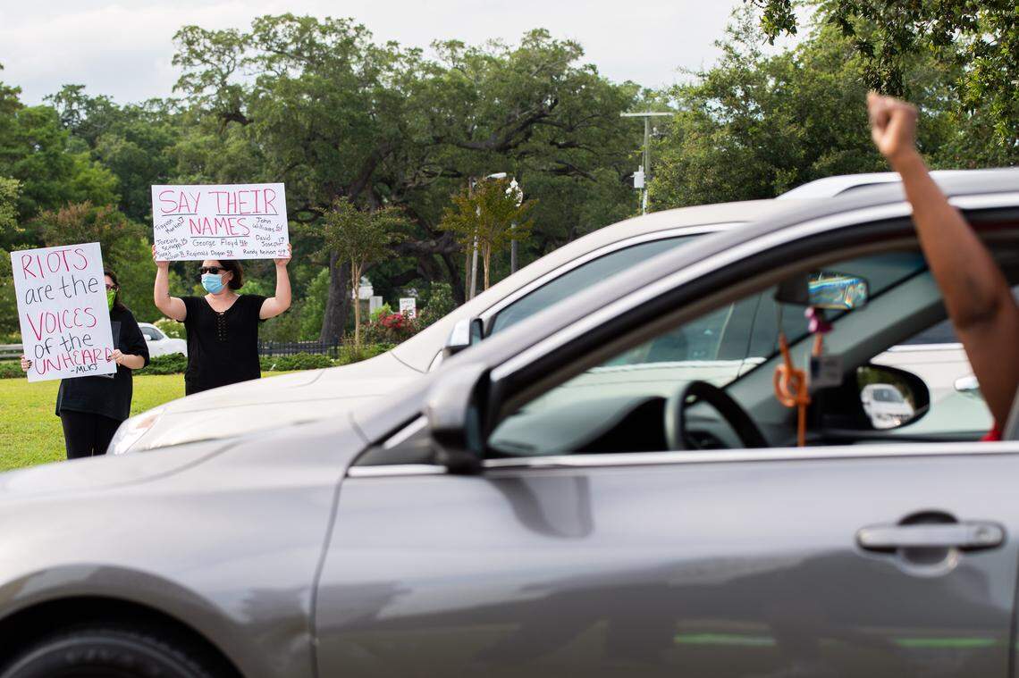 One sign says “Riots are the voices of the unheard - MLKJ (Martin Luther King Jr.)” Another sign says “Say their names” and lists other black people killed by police and their ages: Trayvon Martin 17, Jorevis Scruggs 15, Janet Wilson 31, Reginald Dogan 53, John Williams 61, David Joseph 17, and Randy Nelson 49.