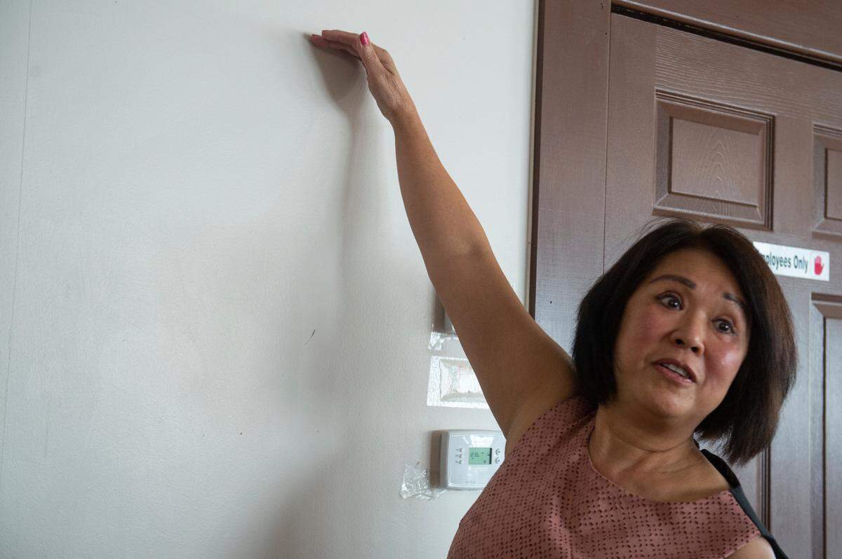 Owner Kim Pham holds up her hand to demonstrate how high the water came up inside her restaurant during Hurricane Katrina at Kim Long in Biloxi on Wednesday, Aug. 2, 2023.