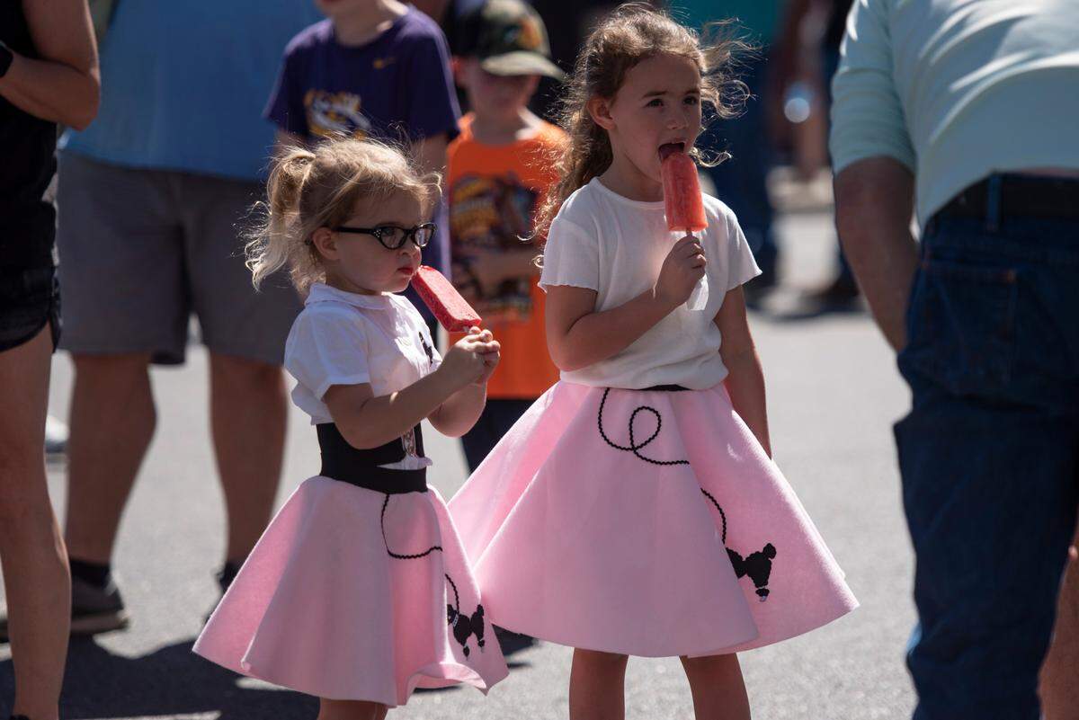 Girls in pink poodle skirts cool off with popsicles during View the Cruise in Downtown Gulfport during Cruisin’ The Coast2022.