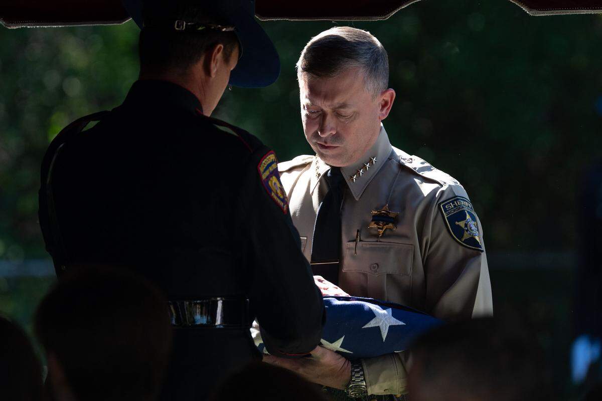 Jackson County Sherriff John Ledbetter is handed a trifold flag Wednesday during the funeral for Jackson County Deputy Joshua Brashears.