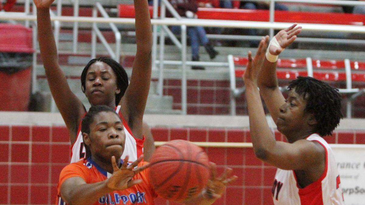 JOHN FITZHUGH/SUN HERALD 
 Gulfport's Aarmanii McDaniel dishes off a pass as Biloxi's Dominique Evans and Anna Thigpen, right, defend during the first period of their game at Biloxi on Friday Jan. 22, 2015.