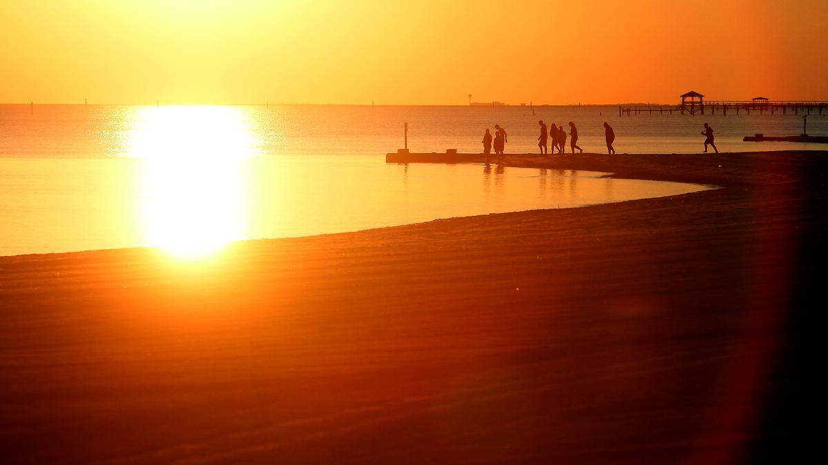 A group of beach goers watches as the sun sets over the water in Pass Christian on Saturday, December 17, 2011.