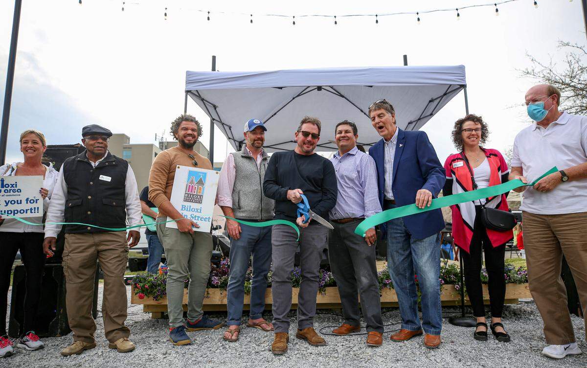 A green ribbon was cut to officially open the District Green on Howard Avenue, a large outdoor green space with seating, a stage and cafe lights.