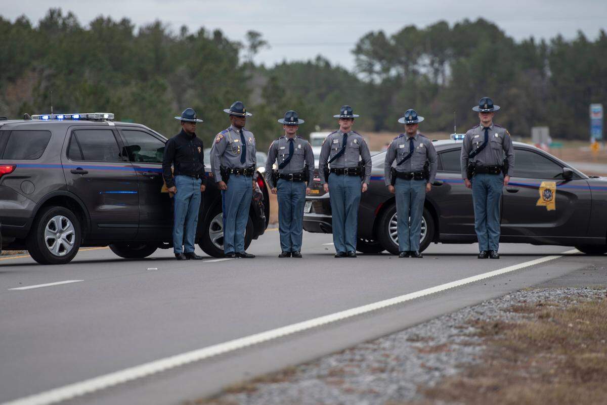 State troopers stand at attention as a procession escorting George County Sheriff’s officer Jeremy Malone, who was killed on Thursday, arrives at Moments Funeral Home in Lucedale on Friday, Jan. 5, 2024.