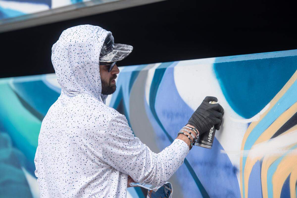 Niko Cook, a local Ocean Springs artist, helps install a mural by Douglas Hoekzema, also known as Hoxxoh, on a parking garage at the new OS 1515 development in downtown Ocean Springs on Tuesday, Oct. 29, 2024.