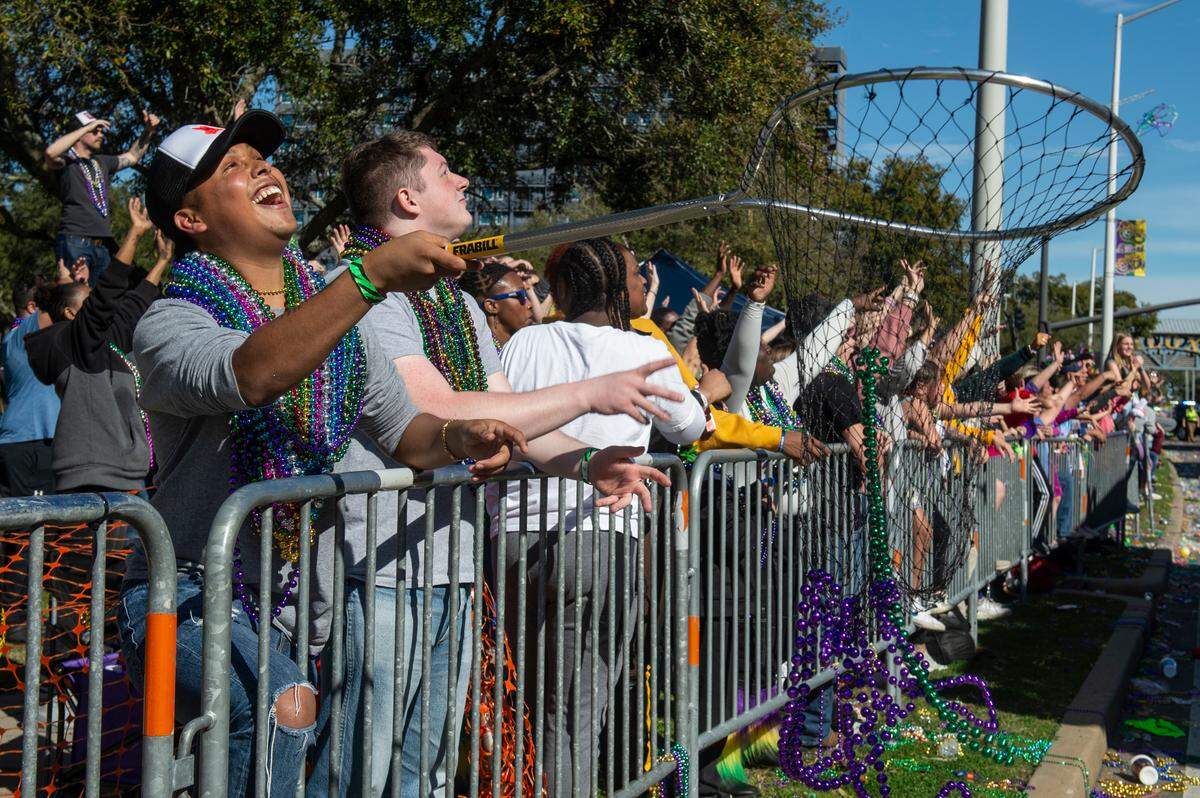 Paradegoers catch beads during the Gulf Coast Carnival Association’s Mardi Gras parade in Biloxi on Tuesday, Feb. 13, 2024.
