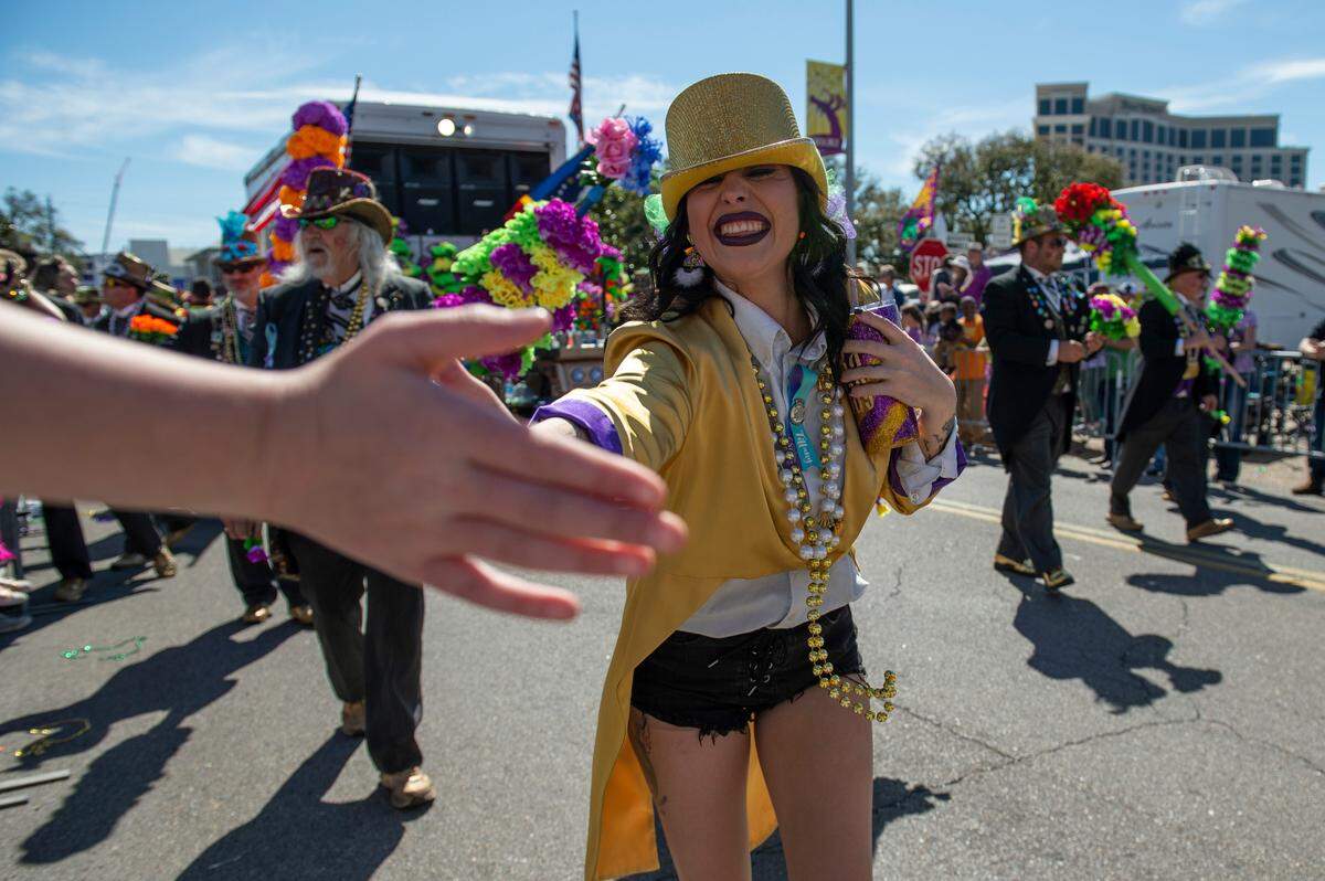 A member of the Ole Biloxi Marching Club high fives a parade watcher during the Gulf Coast Carnival Association Mardi Gras Parade in Biloxi on Tuesday, March 1, 2022.