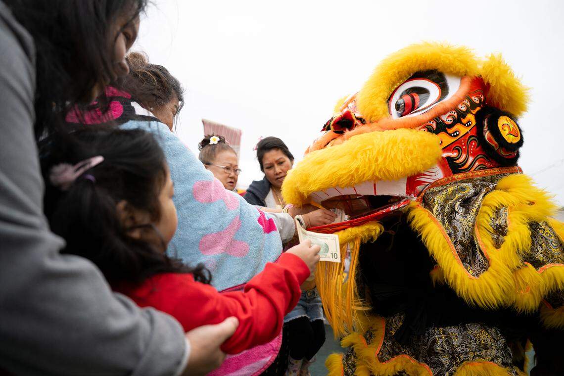 A man dressed as a dragon accepts money as he performs during Songkran at the Wat Buddhametta Mahabaramee in Gautier on Sunday, April 19, 2026.