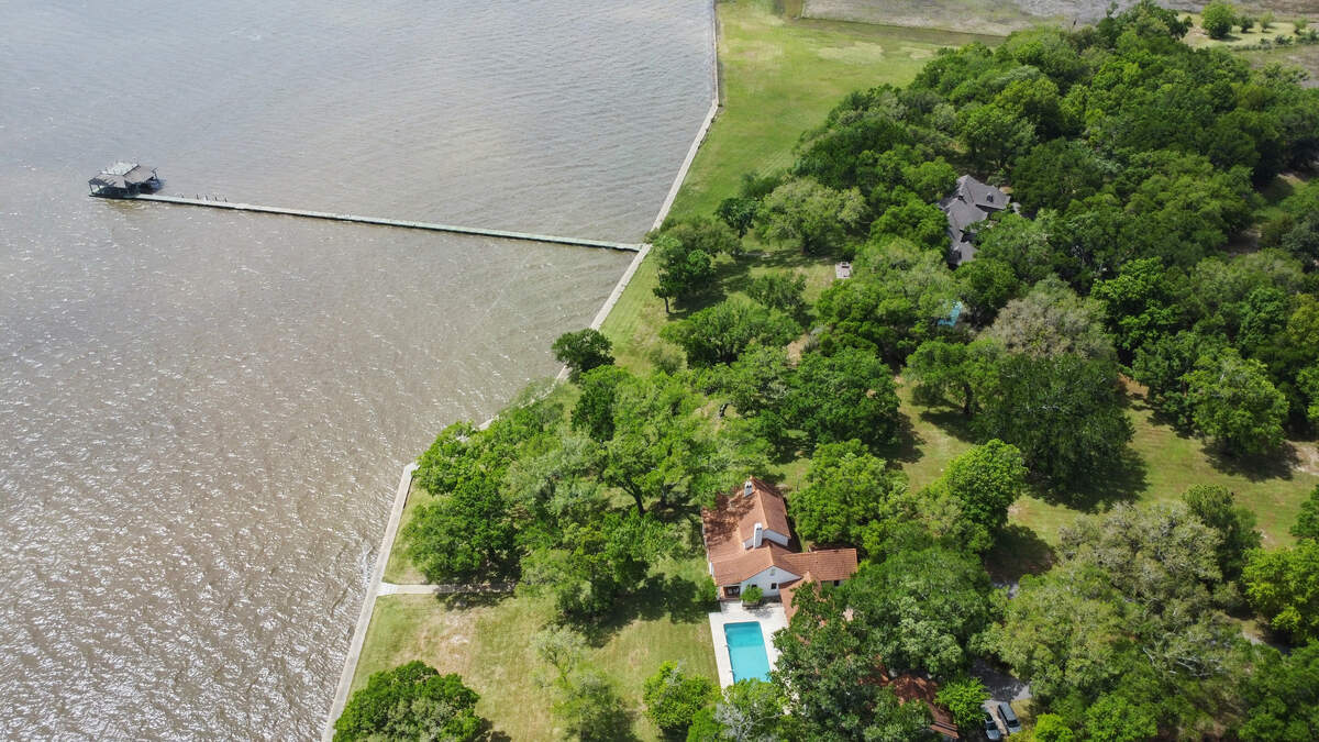This aerial photo showcases the boathouse, concrete bulkhead sidewalk and two houses on 93 acres for sale on the Ocean Springs waterfront. The property, believed to be the most expensive listing in Mississippi, sits on a peninsula backed by Davis Bayou.