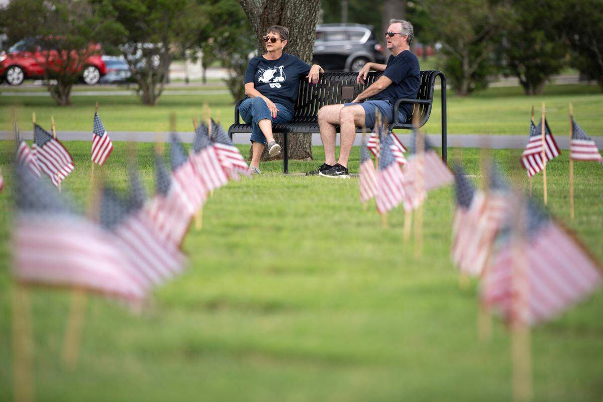 Volunteers relax after helping to place thousands of tiny American flags on the graves of American service members at Biloxi National Cemetery in Biloxi ahead of Memorial Day on Saturday, May 25, 2024.