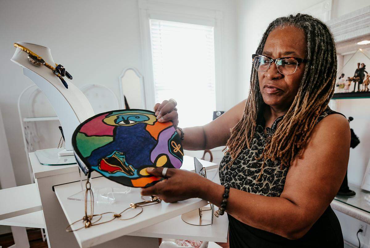 Sabrina Stallworth, a Biloxi-born artist back home after years living in Atlanta, shows off a leather purse she designed and painted. Her art gallery and shop, All Bottled Up By Bre’, shares the space at Champagne, Art & CBD on Howard in Biloxi.