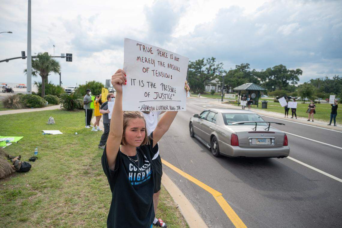A protester holds a sign that reads “True peace is not merely the absence of tension, it is the presence of justice - Martin Luther King Jr.”